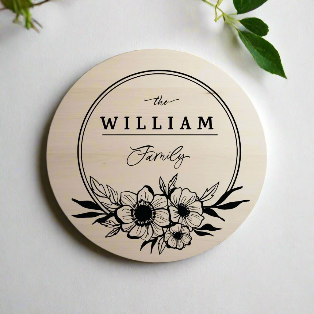 Round beige coaster with black floral design and 'the WILLIAM Family' text on a white background