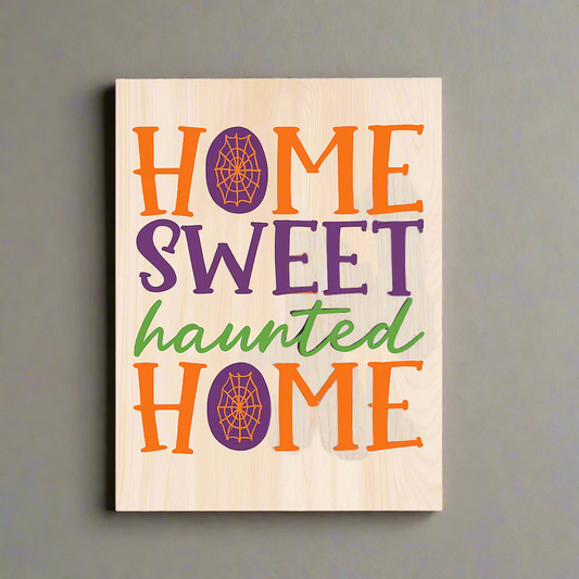Wooden sign with 'Home Sweet Haunted Home' text in Halloween colors on a white background